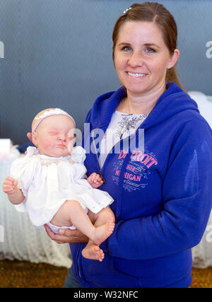 Layton, Utah, USA. 11th July, 2019. DEBBIE SNIDER poses with her reborn doll during the 6th Annual R.O.S.E International Doll Expo, a showcase for ultra realistic ''reborn'' baby dolls. Fashioned meticulously from viny and silcone, and weighted with glass beads and other materials for maximum realism, these collectible dolls have also been employed as emotional, cuddle therapy for dementia patients. Credit: Brian Cahn/ZUMA Wire/Alamy Live News Stock Photo