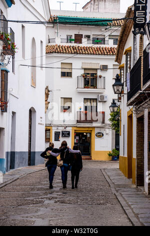 Three friends walking down a typical Spanish town residential street of Cordoba and a great example of the Pueblo Blanco (White Village) areas in Anda Stock Photo