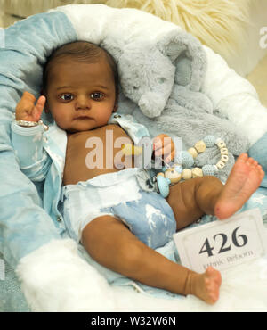 Layton, Utah, USA. 11th July, 2019. A reborn baby doll is displayed in the contest hall at the 6th Annual R.O.S.E International Doll Expo, a showcase for ultra realistic ''reborn'' baby dolls. Fashioned meticulously from viny and silcone, and weighted with glass beads and other materials for maximum realism, these collectible dolls have also been employed as emotional, cuddle therapy for dementia patients. Credit: Brian Cahn/ZUMA Wire/Alamy Live News Stock Photo