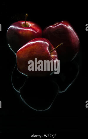 Three apples on a dark environment as part of dark food photogaphy in a black background Stock Photo