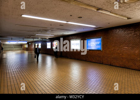 Tokyo, USA - April 4, 2019: Shinjuku Subnade shopping mall underground tunnel passage with business people, businessman in suit walking, commuting to Stock Photo