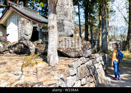 Nikko, Japan - April 4, 2019: Young woman standing by old local ancient shinto shrine of Takumicho in Tochigi prefecture in spring Stock Photo