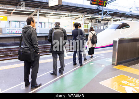 Utsunomiya, Japan - April 4, 2019: Business people, businessman in suit with backpack waiting in line for arriving shinkansen bullet train to Nasuno i Stock Photo