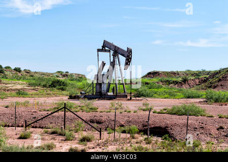 Pumpjack on oilfields in prairies of Post, Texas with machine pumping oil during day Stock Photo