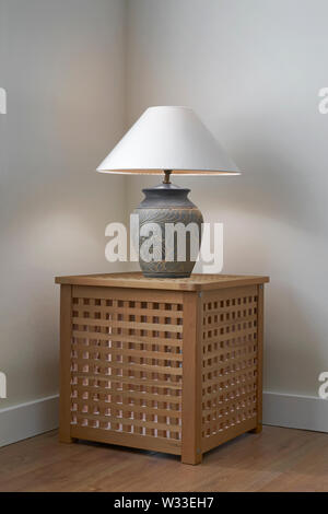 Table lamp on wooden box in corner of room Stock Photo