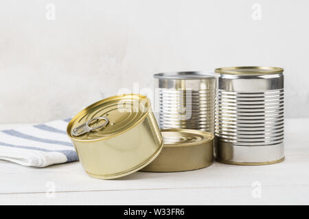 Various closed tin cans with food preserves on a light gray background. Canned food concept. Food donations. Copy space. Stock Photo