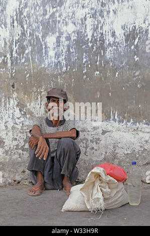 surabaya, jawa timur/indonesia - november 12, 2009: : portrait of an old indonesian homeless  man with beard sitting in front of a wall at pelabuhan k Stock Photo