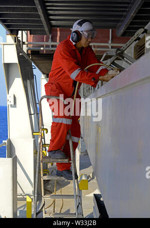 indian ocean, international waters - december 31, 2014 a philippine sailor removing rust at a hatch coaming   of the containership cma cgm vela (imo 9 Stock Photo