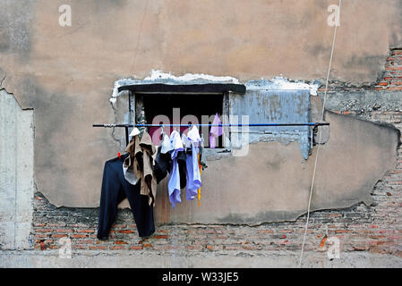 bangkok, thailand -  february 17, 2019:  laundry hanging in front of a window at a shabby building hole for drying in a poor residential area near cha Stock Photo