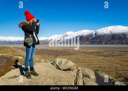 Young woman taking a photograph on DSLR of mountain landscape in New Zealand Stock Photo