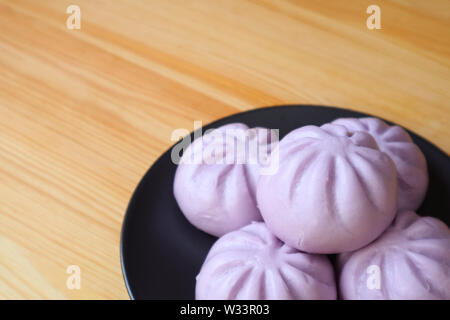 Plate of many purple sweet potato steamed buns on wooden table with copy space Stock Photo