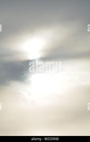 Hazy  diffused sun trying to shine through thin sheet  of cloud, makes abstract  patterns Stock Photo