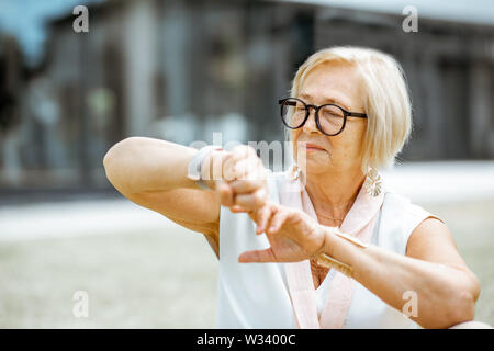 Senior woman using smart watch outdoors. Concept of using modern technologies by elderly people Stock Photo