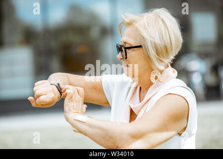 Senior woman using smart watch outdoors. Concept of using modern technologies by elderly people Stock Photo