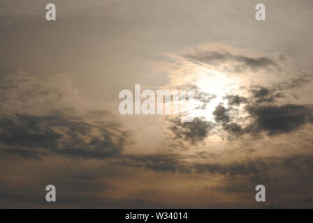 Hazy diffuse sun shining behind  grey clouds in a fuzzy  abstract sky Stock Photo