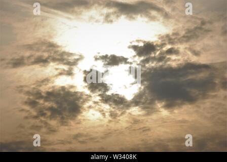 Hazy diffuse sun shining behind  grey clouds in a fuzzy  abstract sky Stock Photo