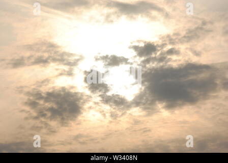 Hazy diffuse sun shining behind  grey clouds in a fuzzy  abstract sky Stock Photo