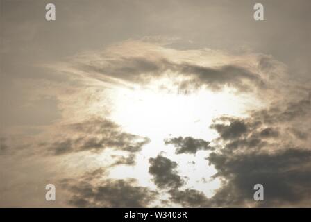 Hazy diffuse sun shining behind  grey clouds in a fuzzy  abstract sky Stock Photo