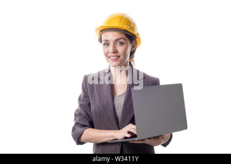 Portrait of happy business engineer woman in yellow helmet standing and using laptop. Stock Photo
