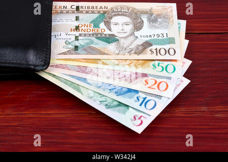 Eastern Caribbean dollars in a black wallet on a wooden background Stock Photo