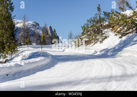 Windiing mountain road covered in snow on a clear winter day Stock Photo