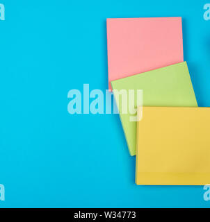 multicolored empty paper square stickers on blue background, copy space Stock Photo