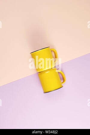 two yellow ceramic cups with a handle on an abstract pastel background, flat lay Stock Photo