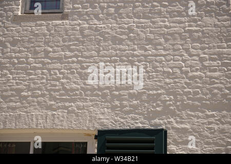Old wall painted white with texture of bricks showing nicely in the sunlight. Stock Photo