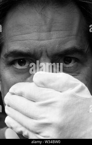 Man's face partially covered by a white glove Stock Photo