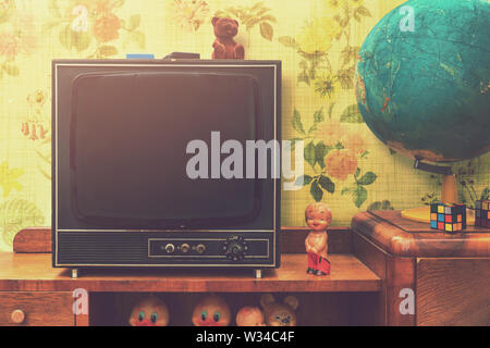 vintage room interior with retro tv and globe on television stand floral wallpaper background Stock Photo