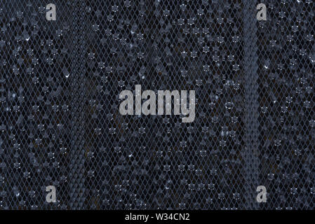 Raindrops collecting on the mesh of a garden table. Stock Photo