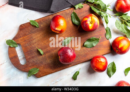 Fresh Nectarines over wood chipper on marble table Stock Photo