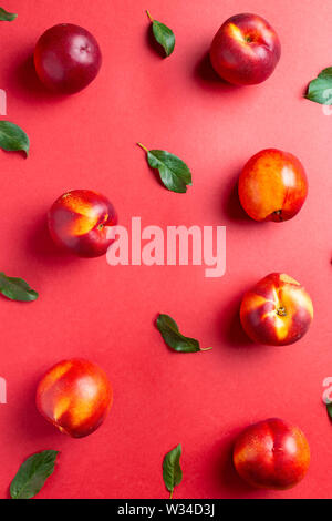 Nectarines and leaves on red background. Useful as food background Stock Photo