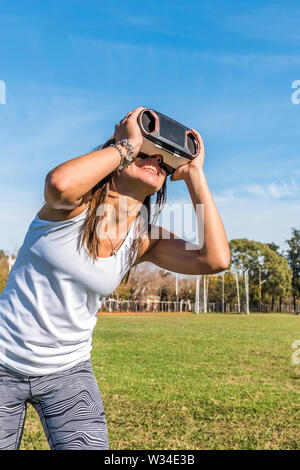 Caucasian woman in the park, brunette with virtual reality mask on a sunny day with blue sky Stock Photo