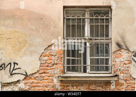 Detail of a facade: window with a crumbled surface and some graffiti, Krakow, Poland Stock Photo