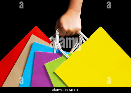 Hand holding colorful paper bags. Isolated on black. Ecological concept. Stock Photo