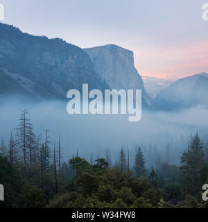 Classic Tunnel View of scenic Yosemite Valley with famous El Capitan and Half Dome rock climbing summits in beautiful misty atmosphere at morning Stock Photo