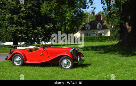 Classic Red MG Motor Car Parked on Village Green. Stock Photo