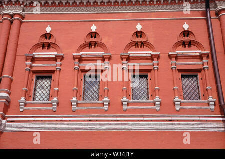 Part of the wall of the facade of a medieval building with barred windows Stock Photo