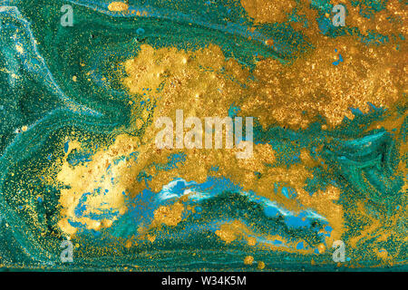 Liquid uneven green marbling pattern with golden glitter and glare of light Stock Photo