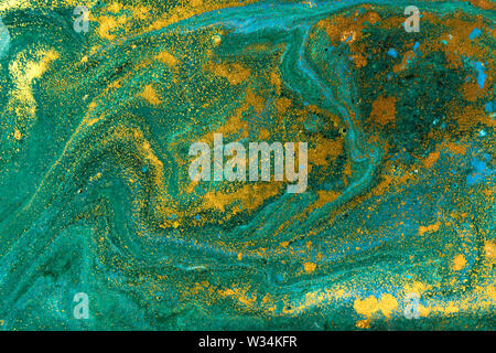 Liquid uneven green marbling pattern with golden glitter and glare of light Stock Photo