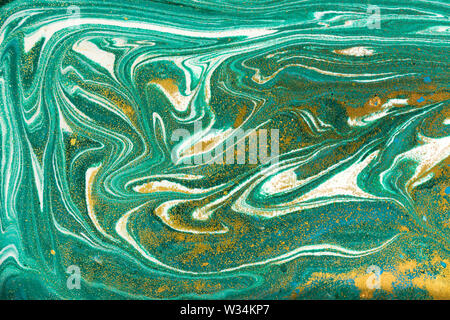 Liquid uneven green marbling pattern with golden glitter and glare of light Stock Photo