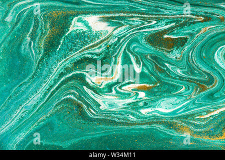 Liquid uneven green marbling pattern with golden glitter and glare of light Stock Photo