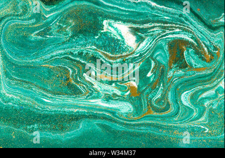 Liquid uneven green marbling pattern with golden glitter and glare of light Stock Photo