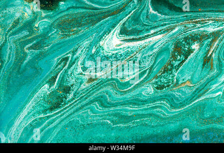 Liquid uneven green marbling pattern with golden glitter and glare of light Stock Photo