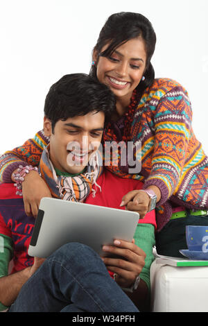 Indian young man using a digital tablet with his wife beside him Stock Photo