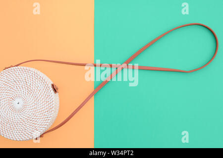 Beautiful round straw handbag on the orange-green background. Trendy handbag. Stock Photo