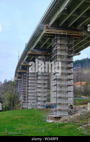 Slovenia: Crew of workers working on repair and maintenance of the substructure on an elevated highway.  Pylons are surrounded by scaffolding Stock Photo
