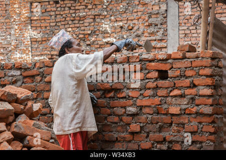 Man rebuilding the wall of a building after an earthquake in Kathmandu Stock Photo