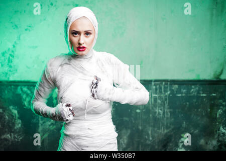 Glamorous mummy. Portrait of a young beautiful woman in bandages all over her body. Halloween or plastic surgery concept, Green light, mummy breaks in Stock Photo